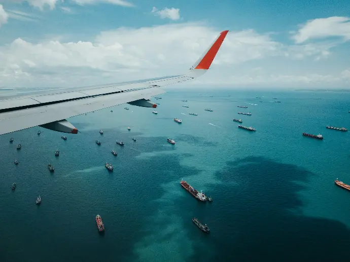 white and red airplane wing over the sea during daytime